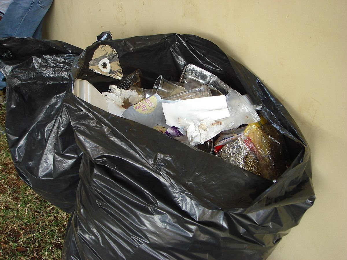 A typical black bin bag from the United Kingdom. One of many garbage bags at a sports event.