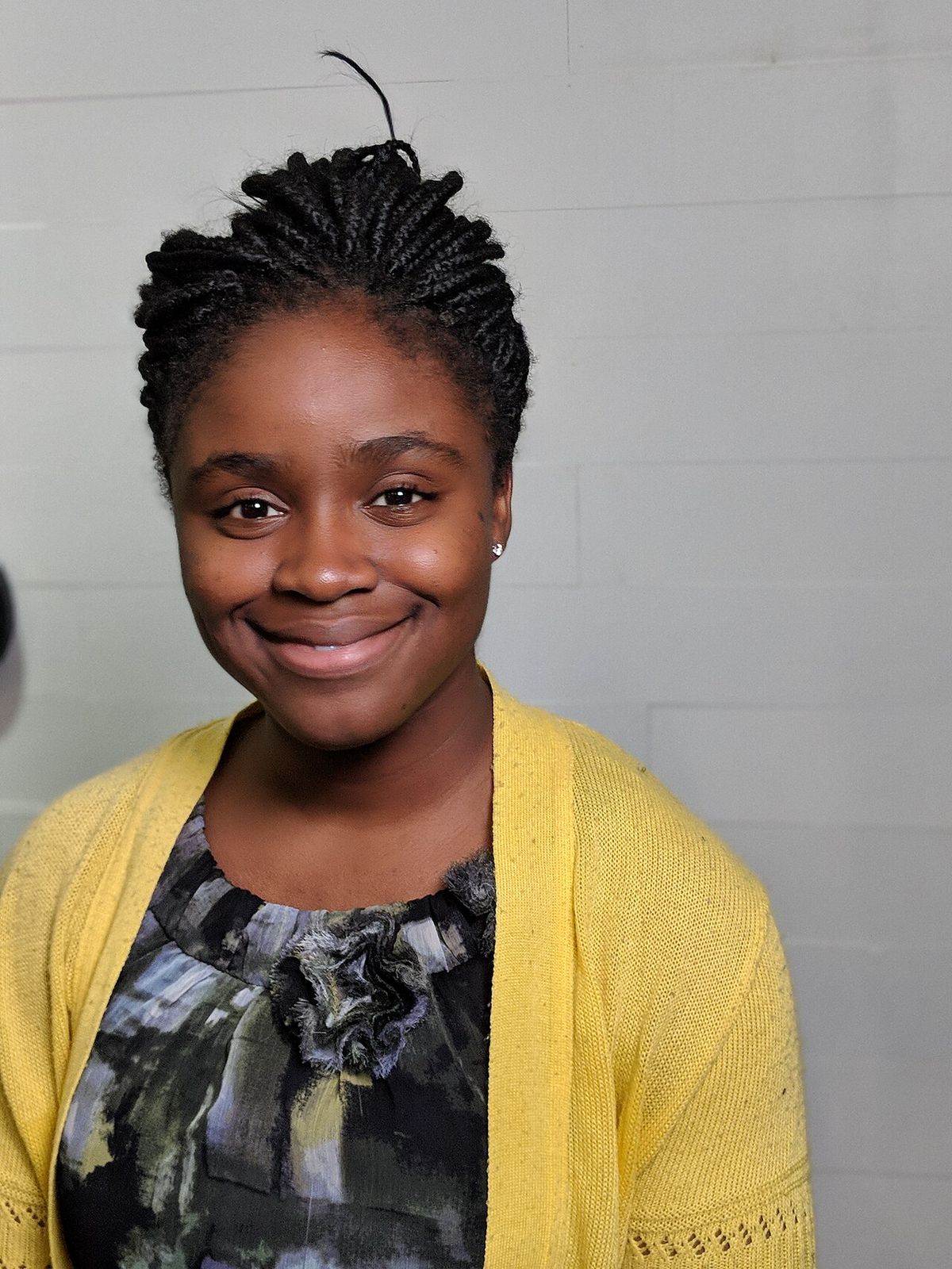 Portrait of Inioluwa Deborah Raji, wearing a yellow cardigan