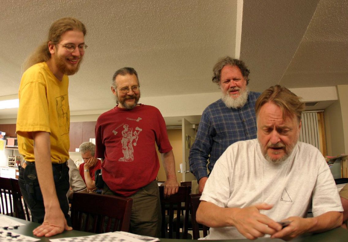 Erik Demaine (left) with Martin Demaine (center) and Bill Spight (background) watch John Conway (foreground) do a card trick at Workshop on